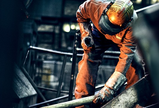 Gießer hält Kupferrohr in die Glut