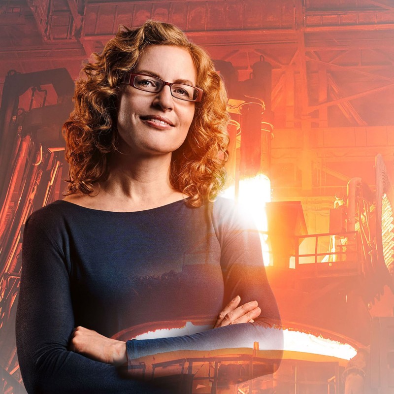 Materialwissenschaftlerin Andrea mit Gießerei und glühendem Kupfer im Hintergrund