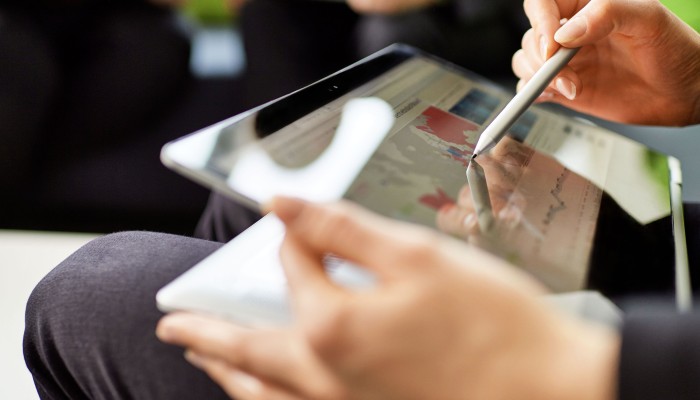 Zwei weibliche Hände halten Tablet und Touchpen