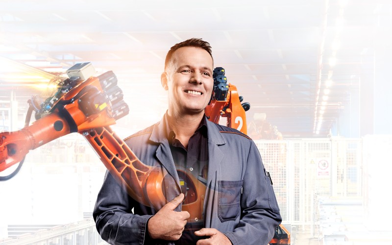Schichtmeister Uwe mit Roboterarm im Hintergrund