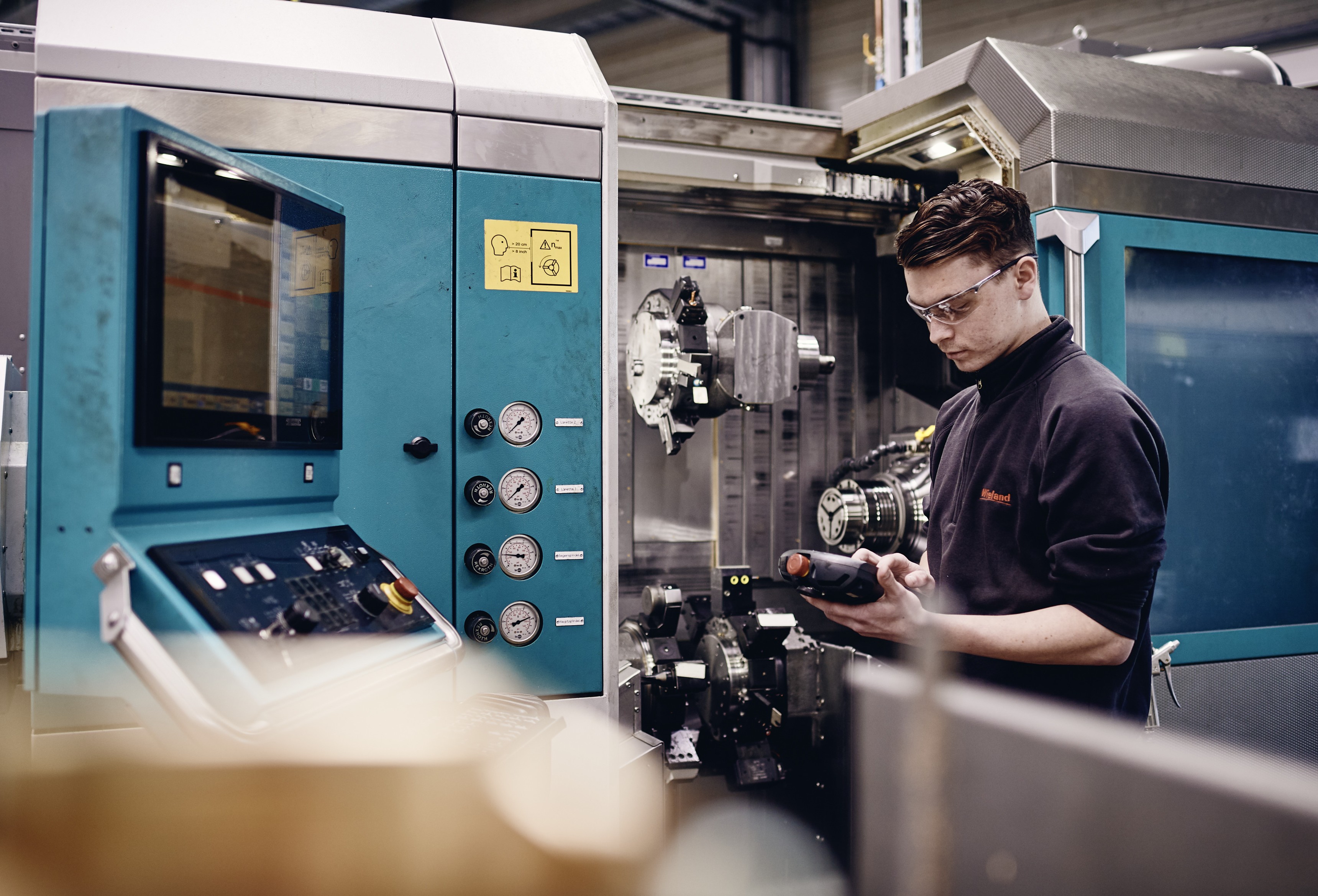 Junger Auszubildender arbeitet an Maschine