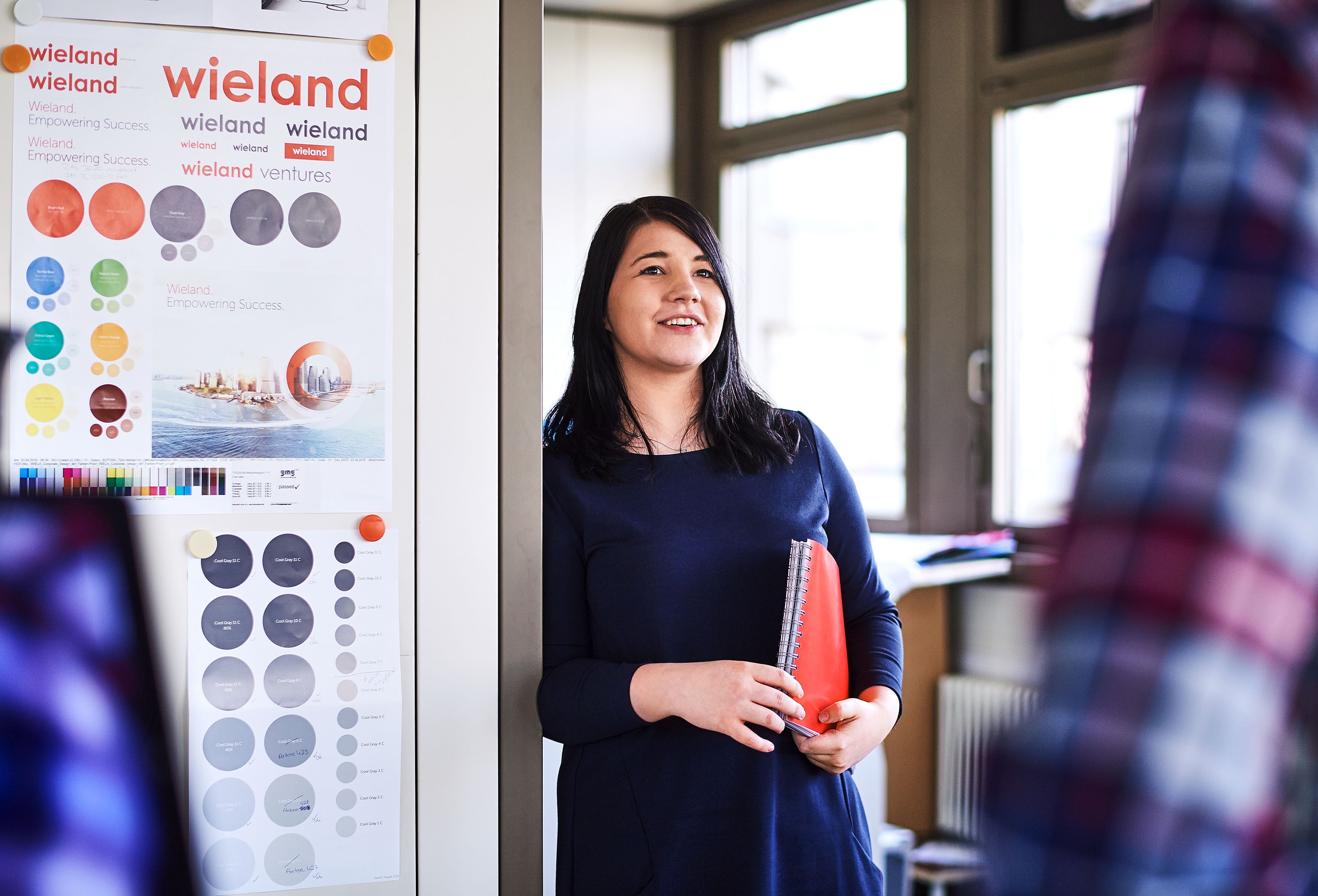 Lächelnde Mitarbeiterin mit Mappe unter dem Arm