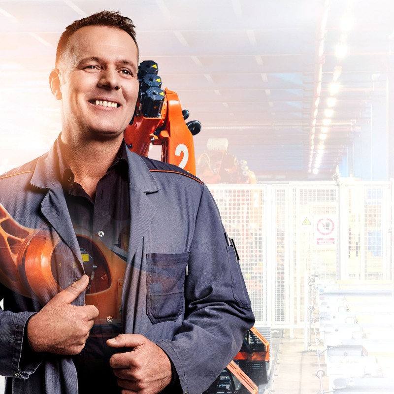 Schichtmeister Uwe mit Roboterarm im Hintergrund