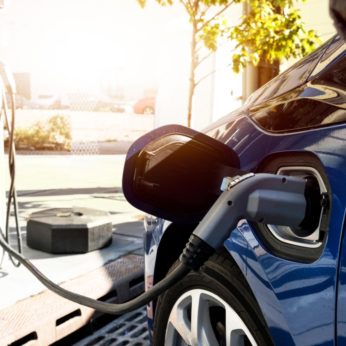 E-Auto wird an einer Ladestation über einen Stecker aufgeladen