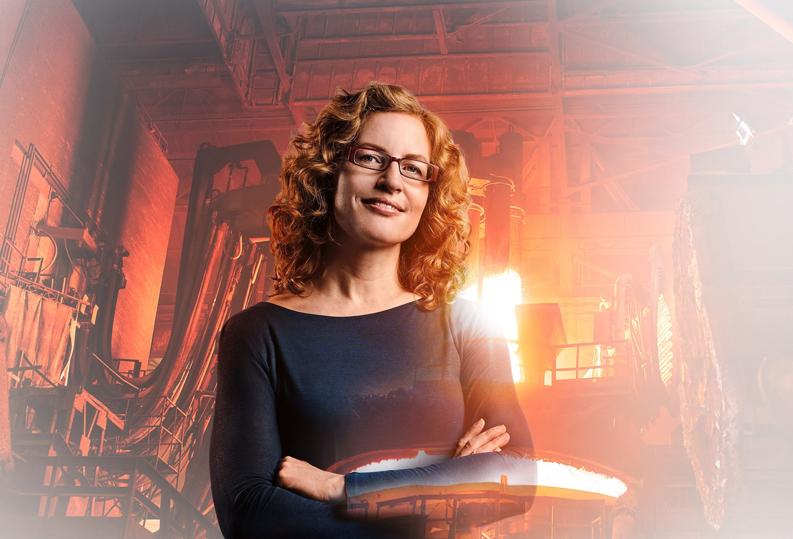 Materialwissenschaftlerin Andrea mit Gießerei und glühendem Kupfer im Hintergrund