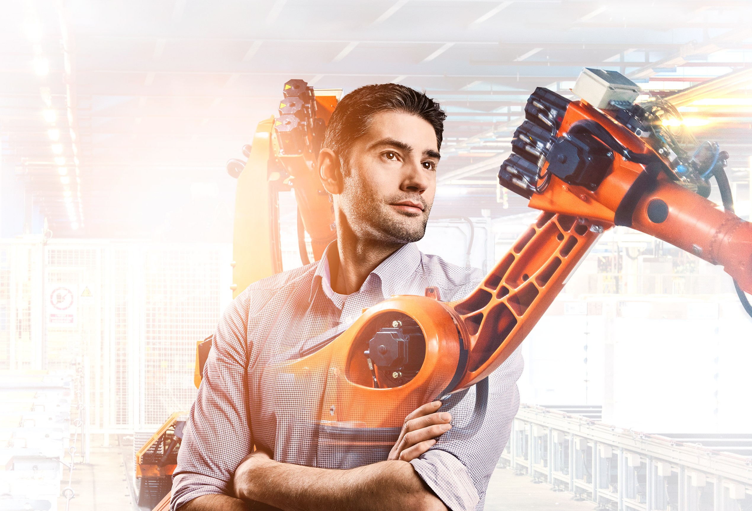 Konstrukteur Fabian mit Fertigungsroboter im Hintergrund