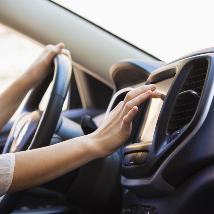 Frau am Steuer eines Autos tippt mit dem Finger auf das Navigationssystem
