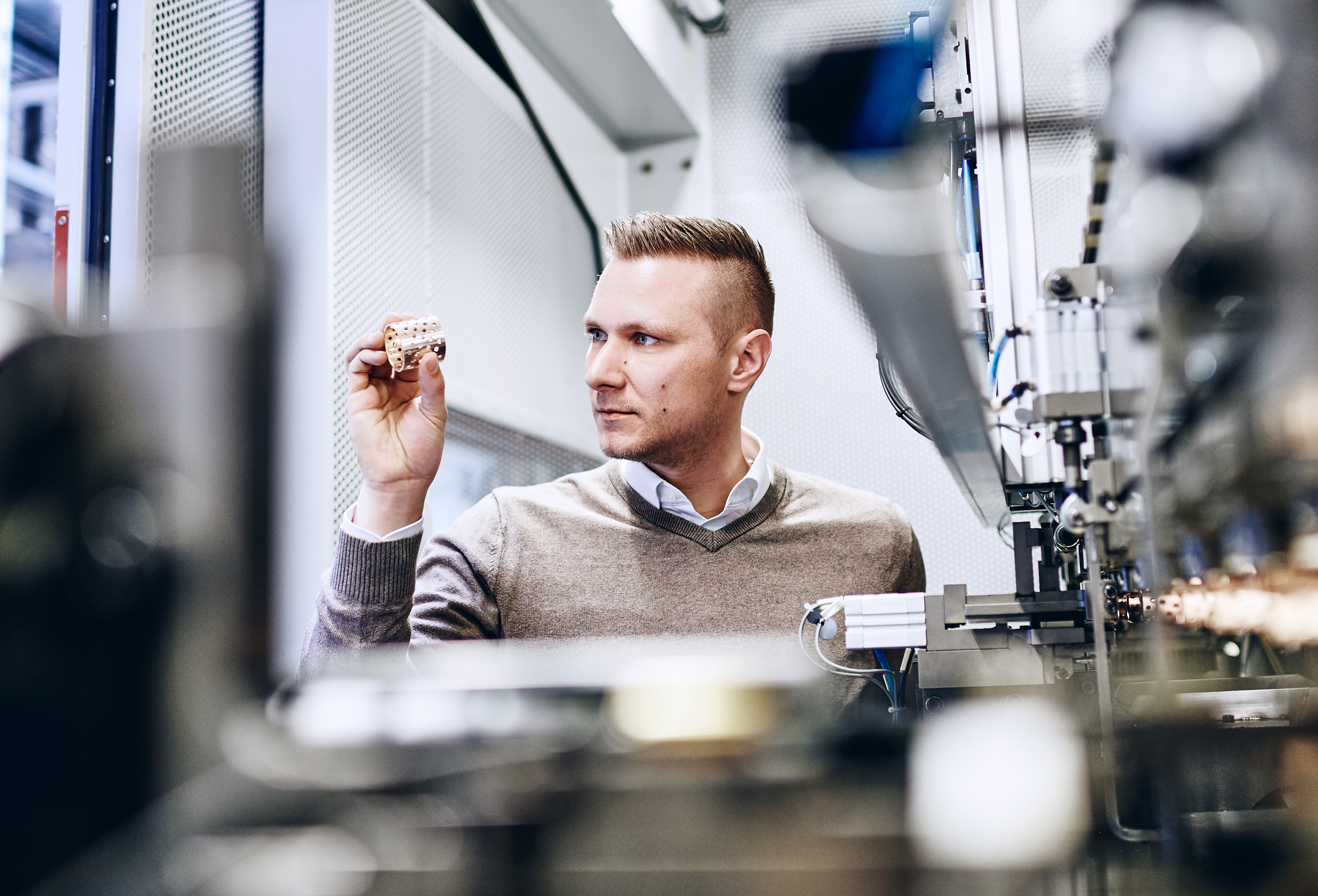 Ingenieur hält Messinghülse prüfend hoch