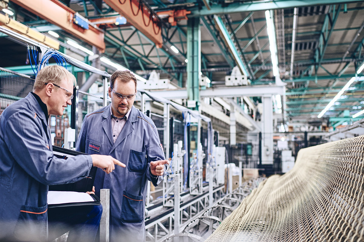 Zwei Ingenieure in Arbeitskleidung besprechend etwas in einer Fertigungshalle