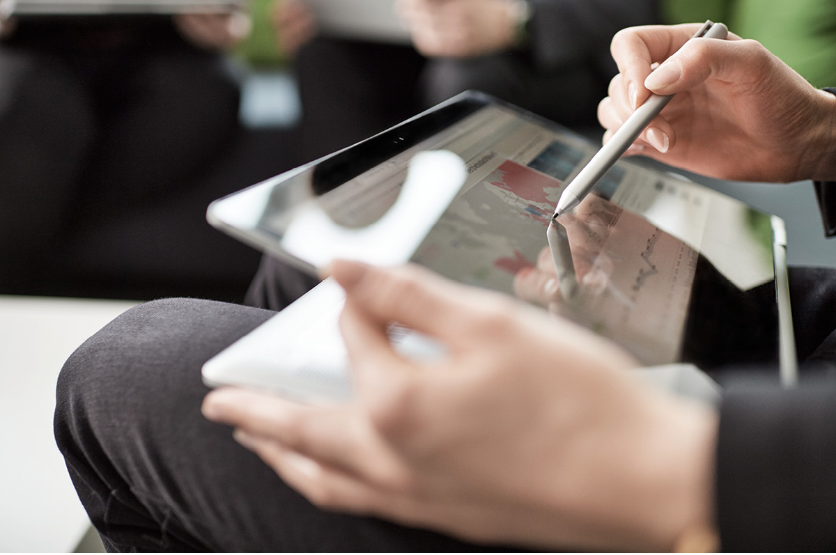 Zwei weibliche Hände halten ein Tablet und einen Touch-Pen
