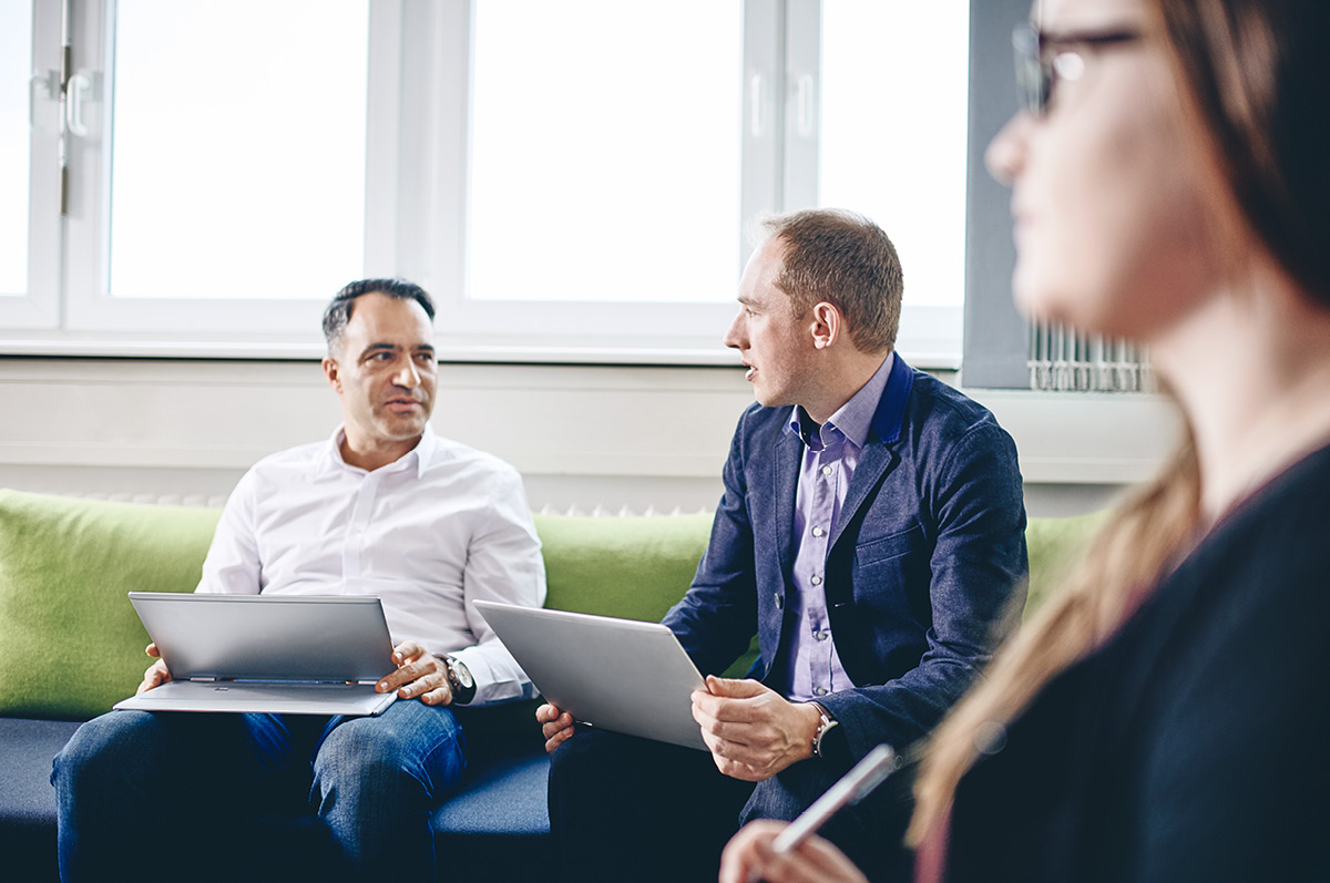 Eine Gruppe IT-Experten sitzt mit Laptops zusammen