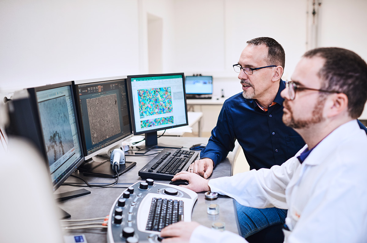 Zwei Materialwissenschaftler schauen Mikrskopaufnahmen am Bildschirm an