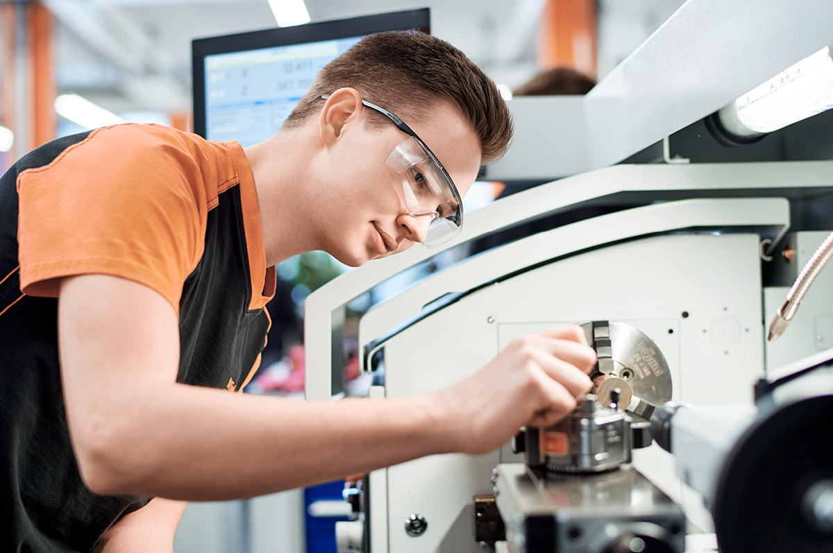 Junger Auszubildender arbeitet an Maschine