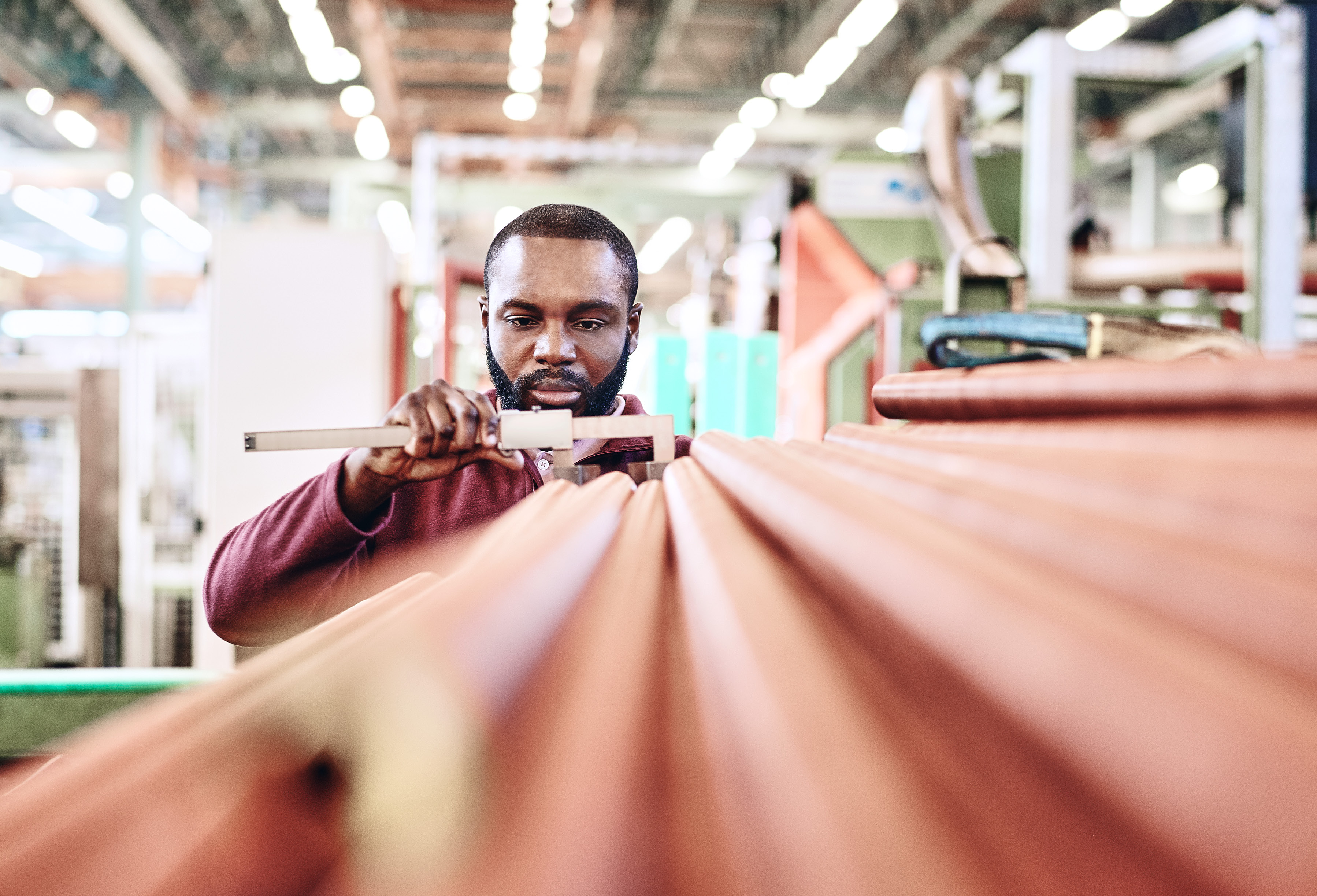 Mitarbeiter prüft Kupferrohre mit Schieblehre