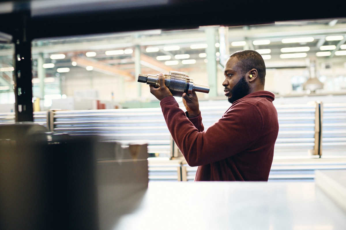 Mitarbeiter in Werkshalle prüft Komponente