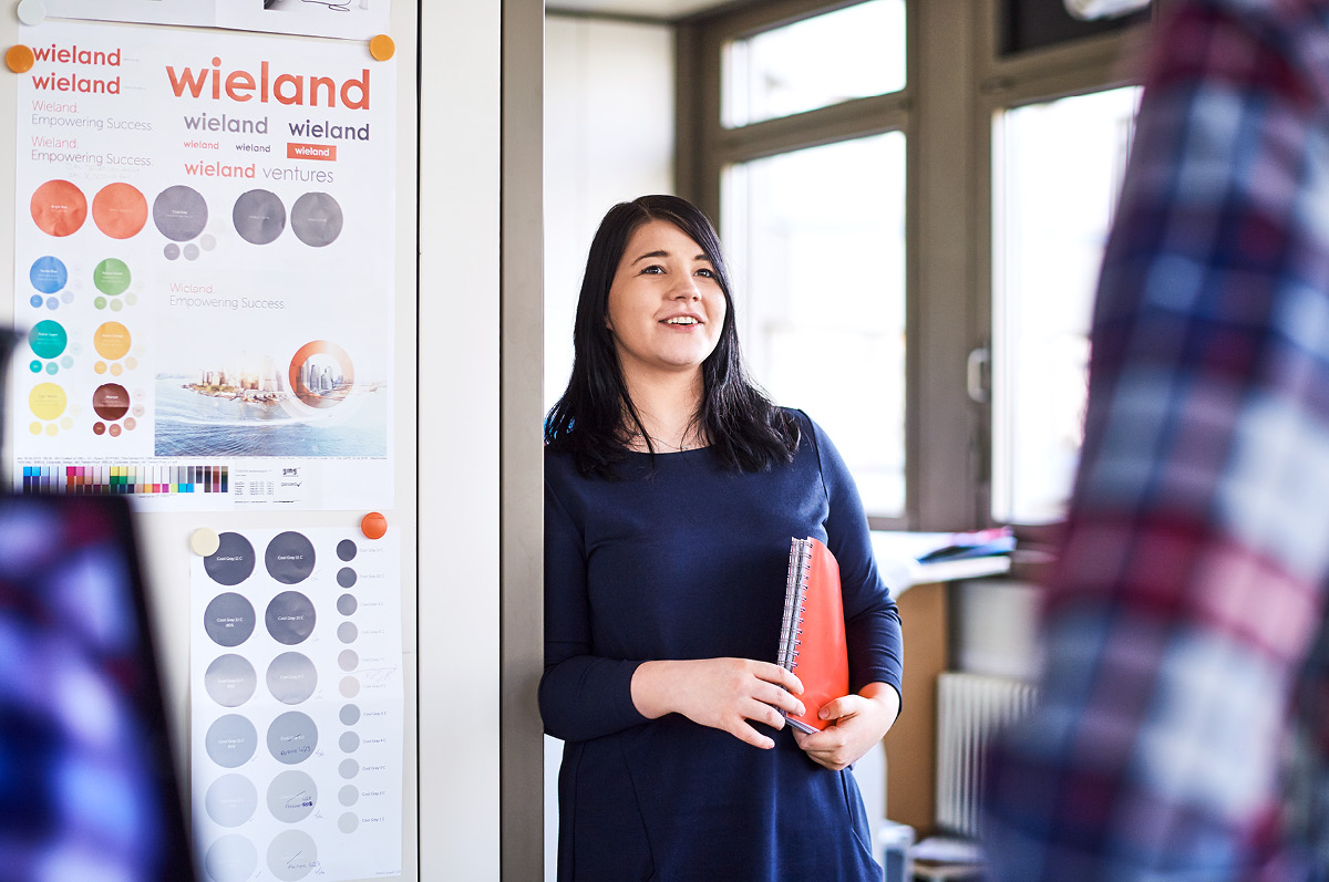 Lächelnde Mitarbeiterin mit Mappe unter dem Arm